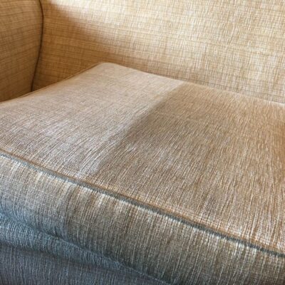 A beige couch with a cushion on top of it.