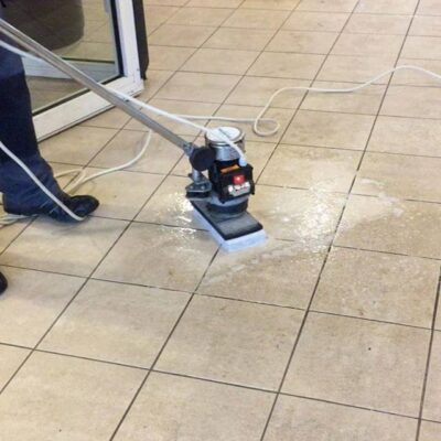 A person cleaning a tile floor with a vacuum cleaner.