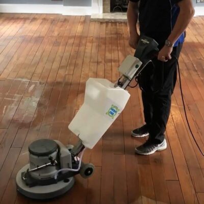 A man cleaning a wooden floor with a machine.