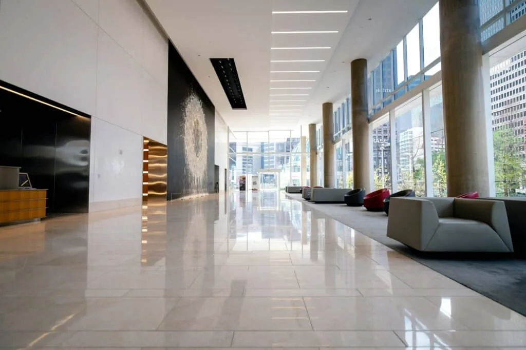 Zero Dry Time Spacious modern lobby with marble floors, large windows, natural light, gray seating, and city buildings visible outside.