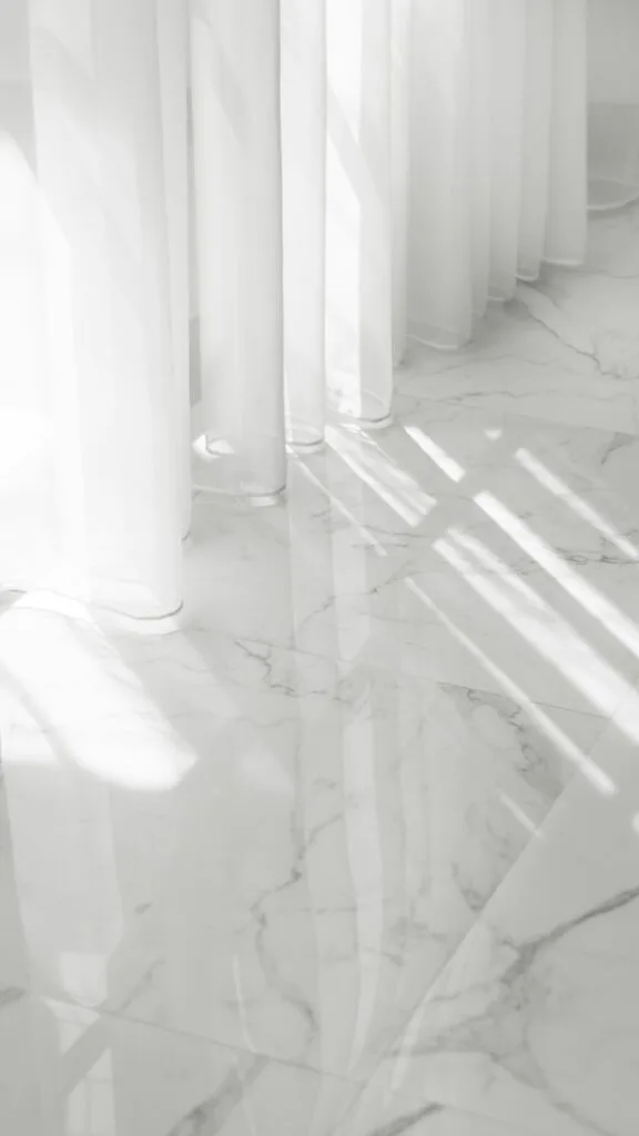 Zero Dry Time Sunlight casts shadows through sheer white curtains onto a glossy, white marble floor with gray veining.